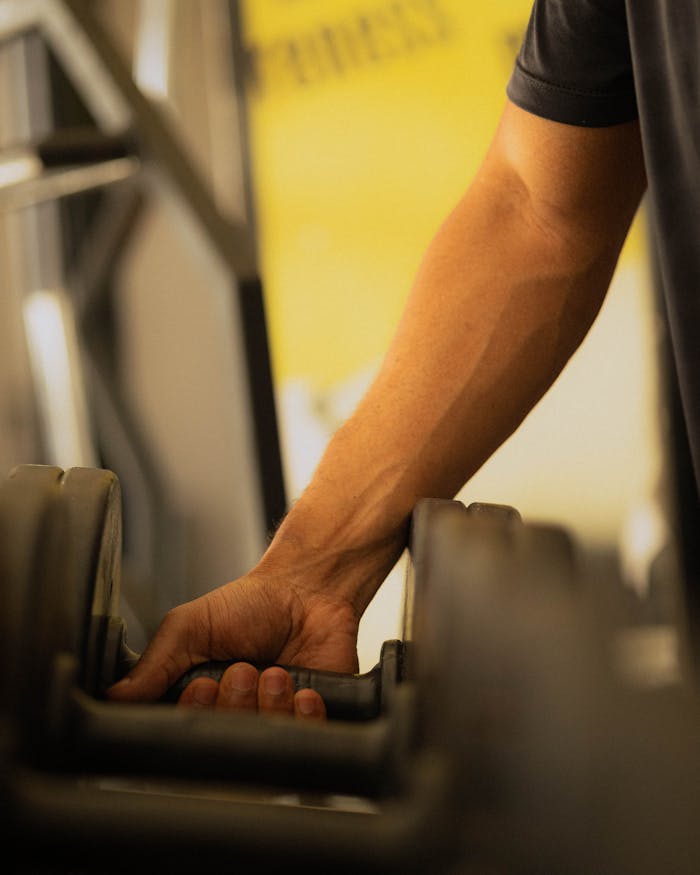 services-01 A muscular arm lifting a dumbbell in a gym setting, emphasizing strength and fitness.